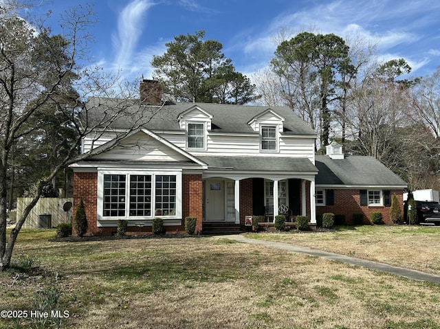 view of front of property featuring a chimney, a front lawn, central AC, and brick siding