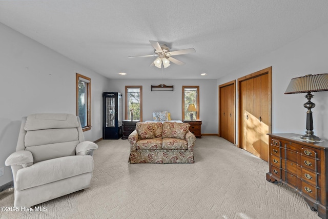 living room with baseboards, a textured ceiling, a ceiling fan, and carpet floors