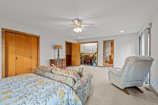 carpeted bedroom with visible vents, baseboards, a textured ceiling, and a ceiling fan