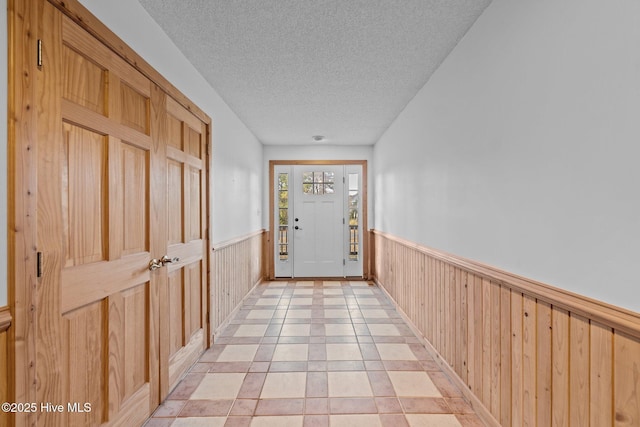 entryway featuring a wainscoted wall, a textured ceiling, and wooden walls