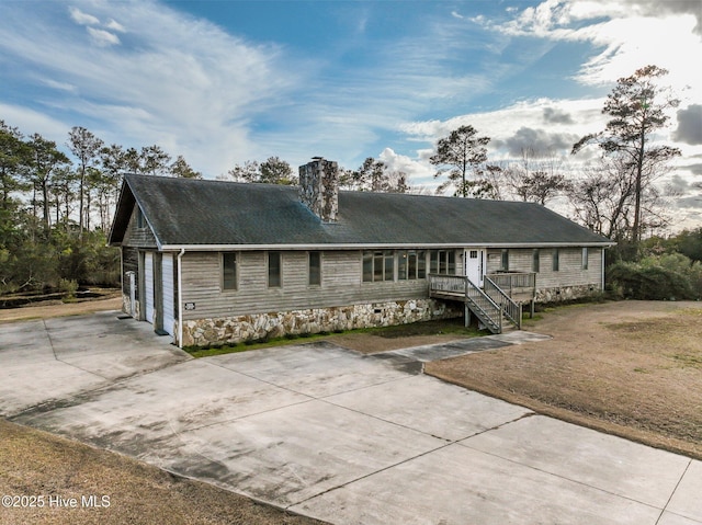 view of front of home featuring a garage, a front lawn, a chimney, and driveway