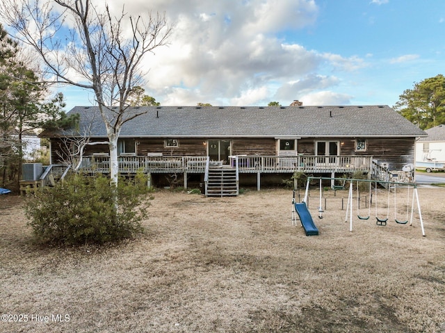 back of property with central air condition unit, a deck, stairs, and a playground