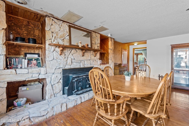 dining area featuring a textured ceiling, wood finished floors, and a fireplace