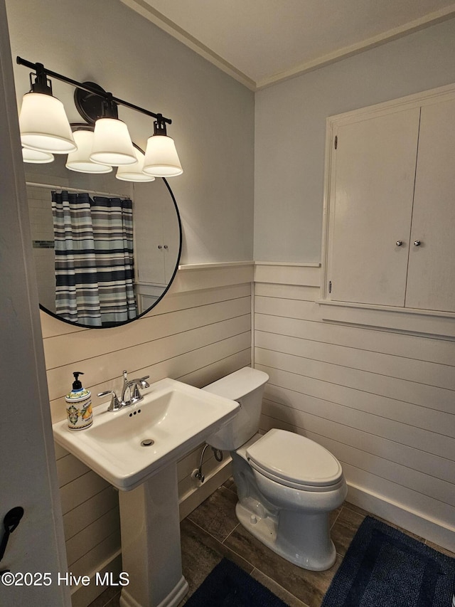 full bathroom with toilet, a wainscoted wall, a shower with curtain, wood finished floors, and crown molding