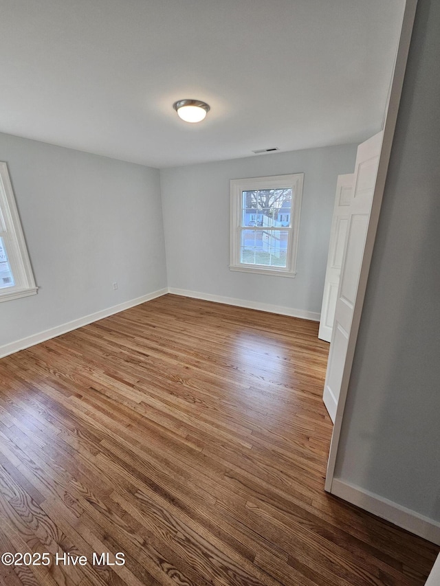 unfurnished bedroom with visible vents, baseboards, and wood finished floors