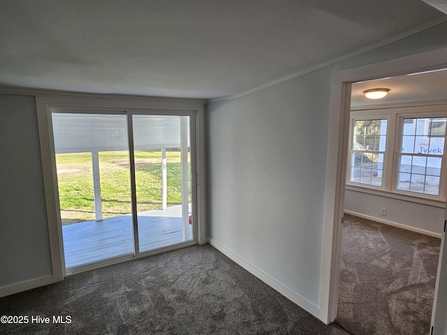 empty room with dark colored carpet, crown molding, and baseboards