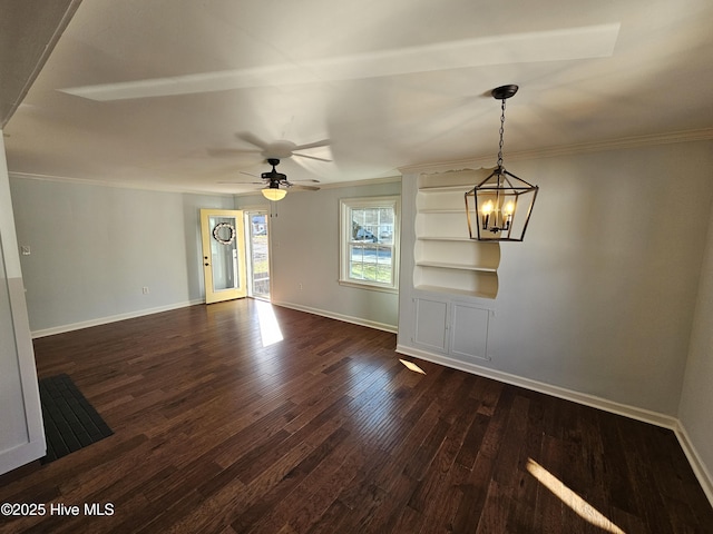 unfurnished living room with ceiling fan with notable chandelier, ornamental molding, dark wood finished floors, and baseboards