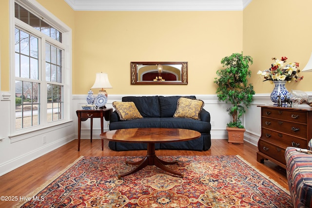 living area featuring a wainscoted wall, crown molding, and wood finished floors