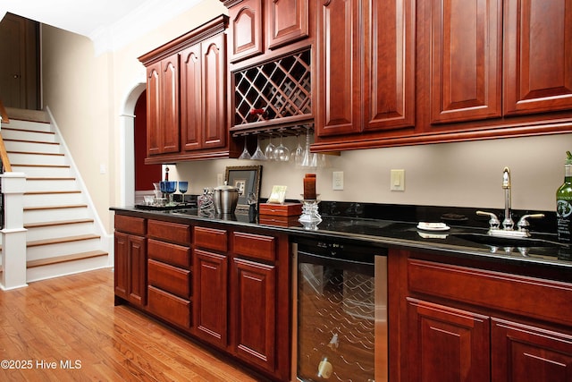 906 Taberna Cir, New Bern, NC 28562 - kitchen featuring dark countertops, dark brown cabinets, wine cooler, light wood-style flooring, and a sink
