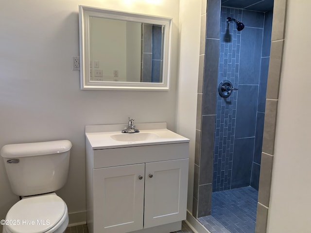 full bath featuring a tile shower, vanity, and toilet