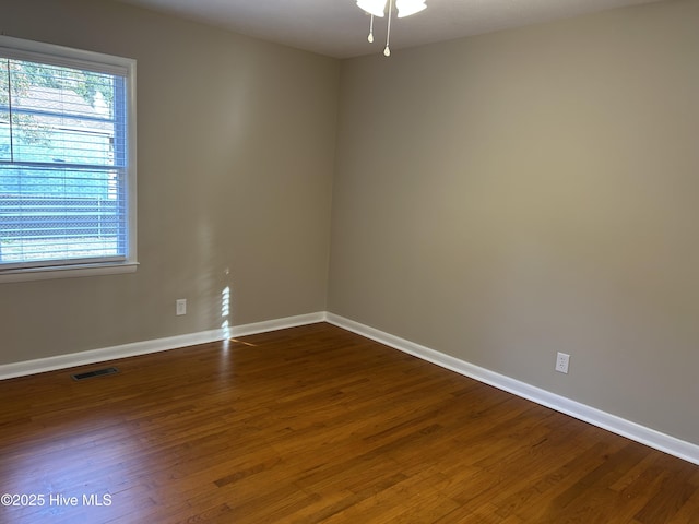 empty room with dark wood-type flooring, plenty of natural light, and baseboards