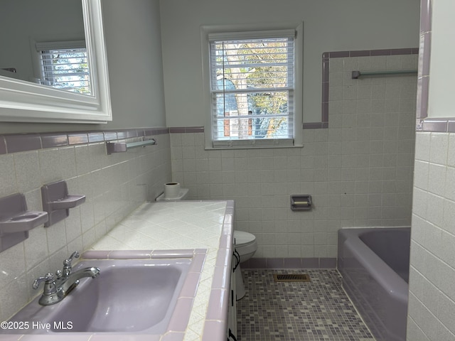 bathroom featuring a bath, a wealth of natural light, a sink, and tile patterned floors