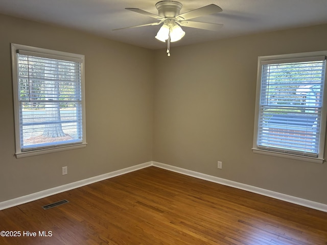 unfurnished room with dark wood-type flooring, visible vents, ceiling fan, and baseboards