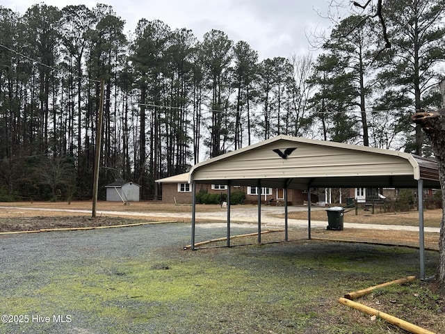 view of home's community with driveway, a carport, an outdoor structure, and a shed