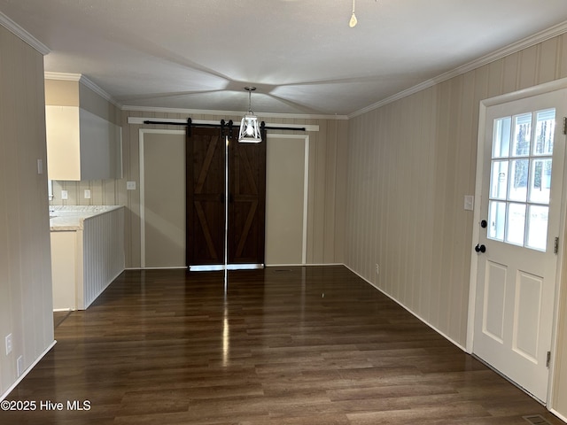 unfurnished dining area featuring dark wood-style floors, a barn door, and crown molding