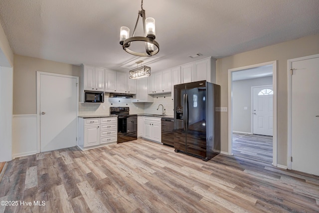 137 El Ogden Dr, Wilmington, NC 28411 - kitchen with light wood-style flooring, a sink, white cabinets, backsplash, and black appliances