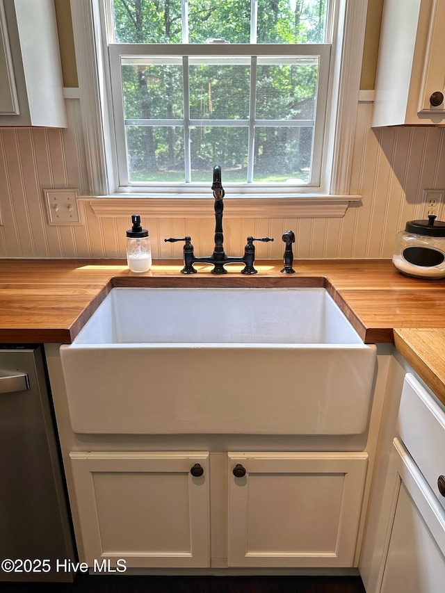 kitchen featuring dishwasher, wooden counters, and a sink