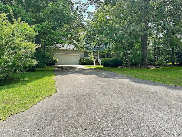 obstructed view of property with an attached garage, a front lawn, and aphalt driveway