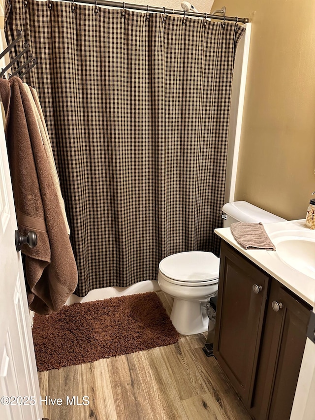 bathroom with a shower with shower curtain, vanity, toilet, and wood finished floors