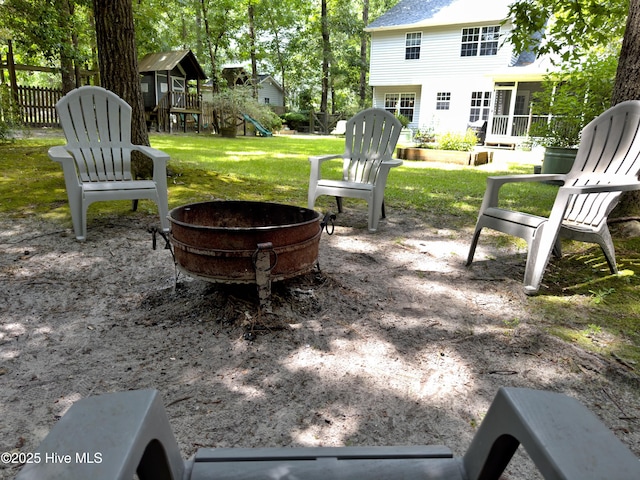 exterior space featuring a playground, fence, a fire pit, and a patio