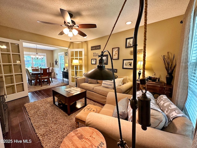 living area featuring dark wood-style flooring, a textured ceiling, and ceiling fan with notable chandelier