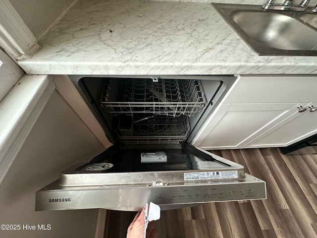 room details featuring dishwashing machine, a sink, and wood finished floors