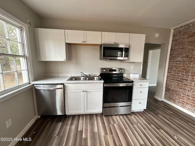kitchen with white cabinets, appliances with stainless steel finishes, dark wood-type flooring, light countertops, and a sink