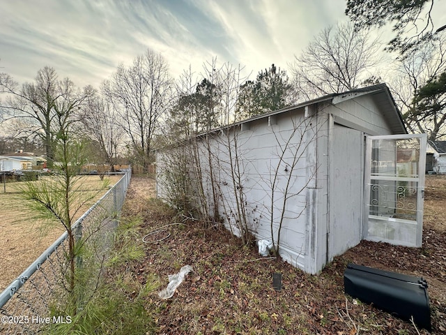 view of property exterior with fence and an outbuilding