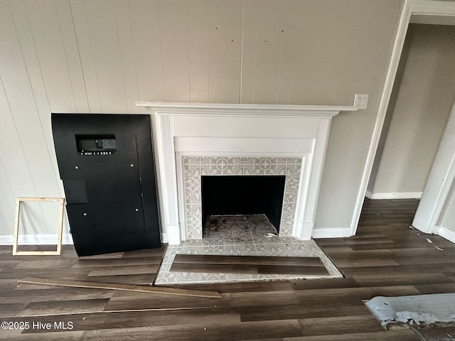 room details featuring baseboards, a tiled fireplace, and wood finished floors