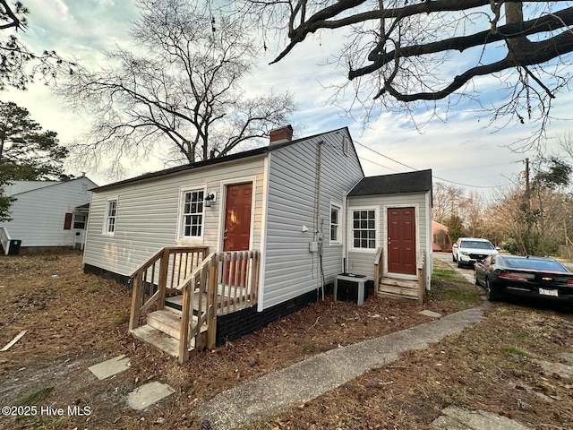 exterior space featuring entry steps, a chimney, and cooling unit
