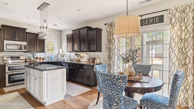 kitchen featuring dark brown cabinets, light wood-style flooring, stainless steel appliances, and backsplash