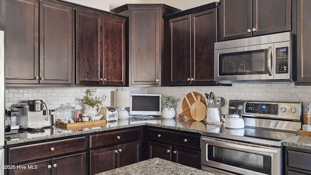 kitchen with light stone countertops, appliances with stainless steel finishes, dark brown cabinets, and backsplash