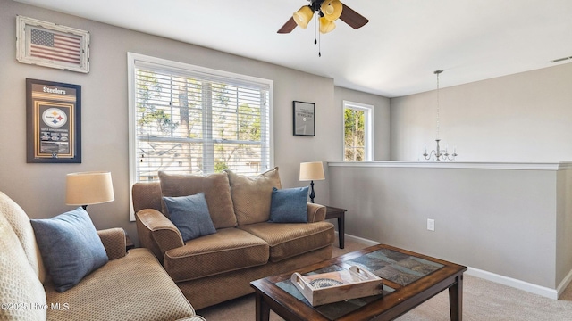 carpeted living room featuring baseboards and ceiling fan with notable chandelier