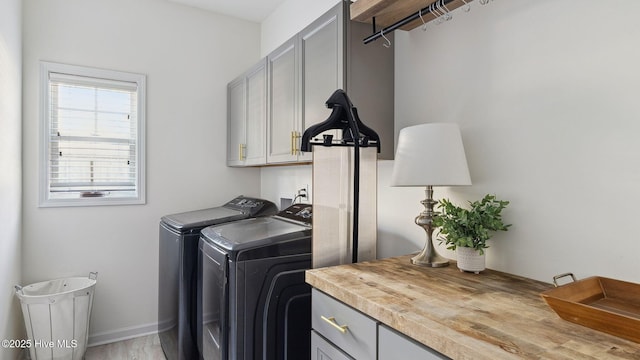 laundry area featuring washer and dryer, cabinet space, and baseboards