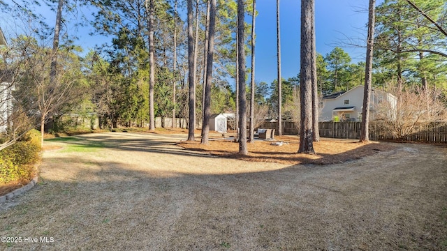 view of community with an outbuilding, fence, dirt driveway, and a shed