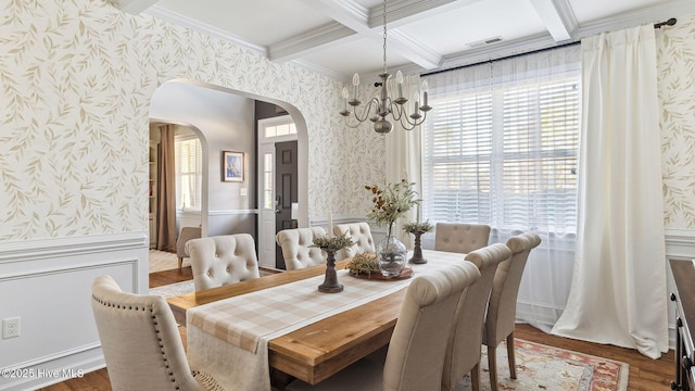 dining area featuring arched walkways, wainscoting, beam ceiling, and wallpapered walls