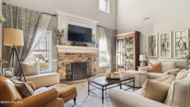 living area with a fireplace, a towering ceiling, and visible vents