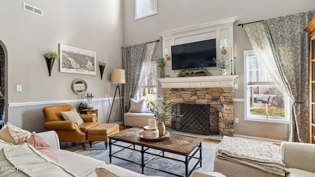 living area with visible vents, a fireplace, arched walkways, and a wealth of natural light