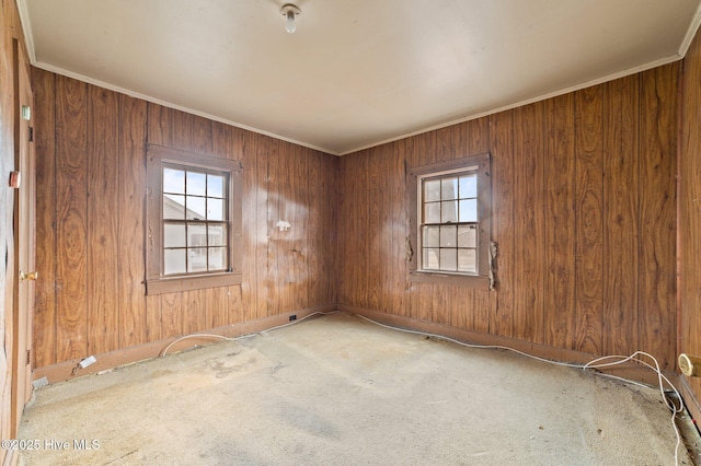 empty room with ornamental molding, carpet, and wooden walls