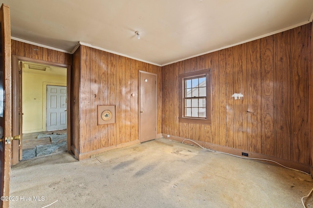 carpeted empty room with wooden walls and crown molding