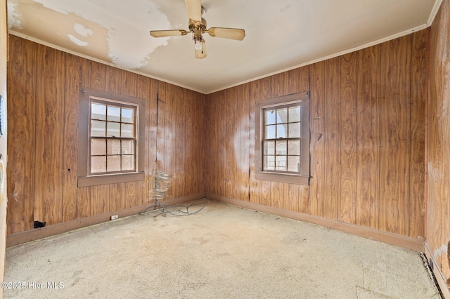 unfurnished room featuring baseboards, ceiling fan, carpet, crown molding, and wood walls