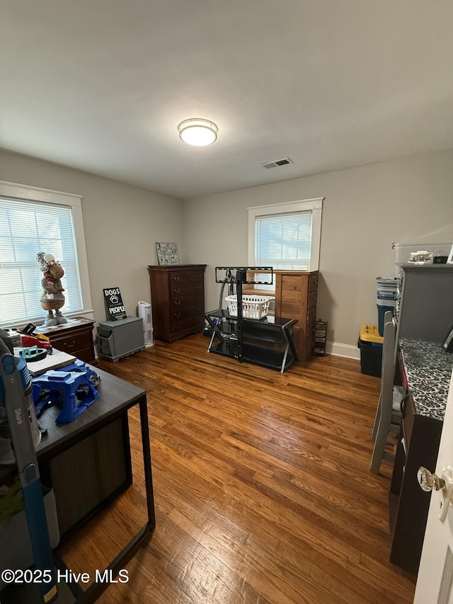 office space featuring a wealth of natural light, wood finished floors, visible vents, and baseboards