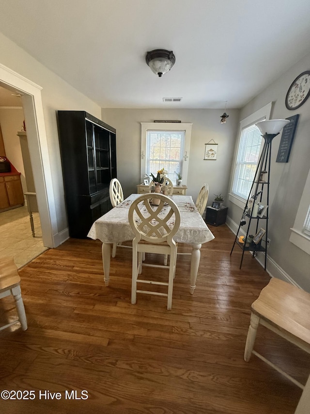 dining area with a healthy amount of sunlight, visible vents, baseboards, and wood finished floors