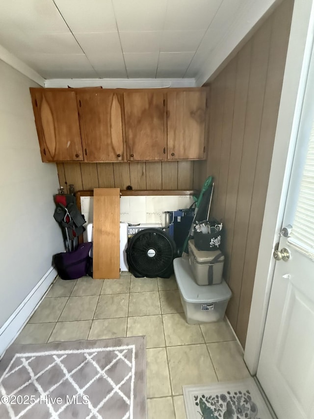 laundry area with light tile patterned floors, wood walls, and baseboards