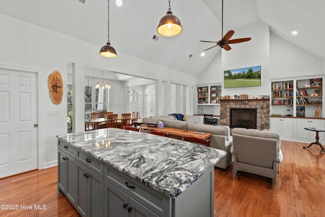 kitchen featuring pendant lighting, a fireplace, light wood finished floors, and gray cabinetry