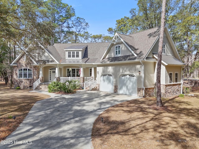 view of front of property featuring a porch, stone siding, roof with shingles, and driveway