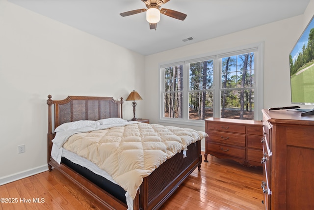 bedroom featuring light wood-style floors, baseboards, visible vents, and ceiling fan