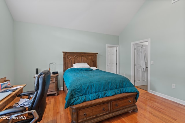 bedroom featuring light wood finished floors, baseboards, and high vaulted ceiling