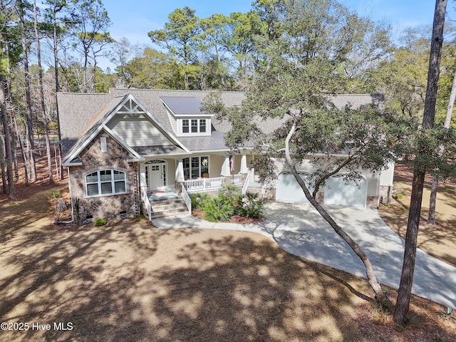 craftsman-style home featuring covered porch, a garage, driveway, stone siding, and crawl space