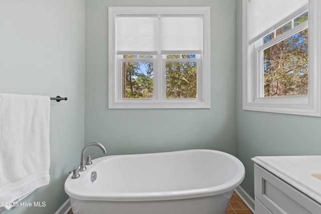 full bathroom with a soaking tub, a healthy amount of sunlight, and vanity